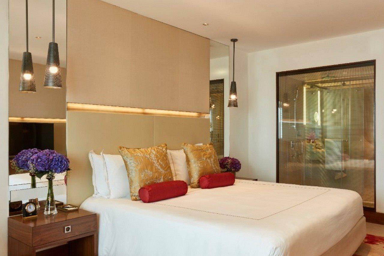 The Taj Mahal Tower, Mumbai Hotel Bagian luar foto The photo shows a modern bedroom with a stylish design. It features a large bed with white linens and decorative pillows in gold and red. The walls are neutral, and there are pendant lights hanging above the bed. To the side, there is a wooden nights