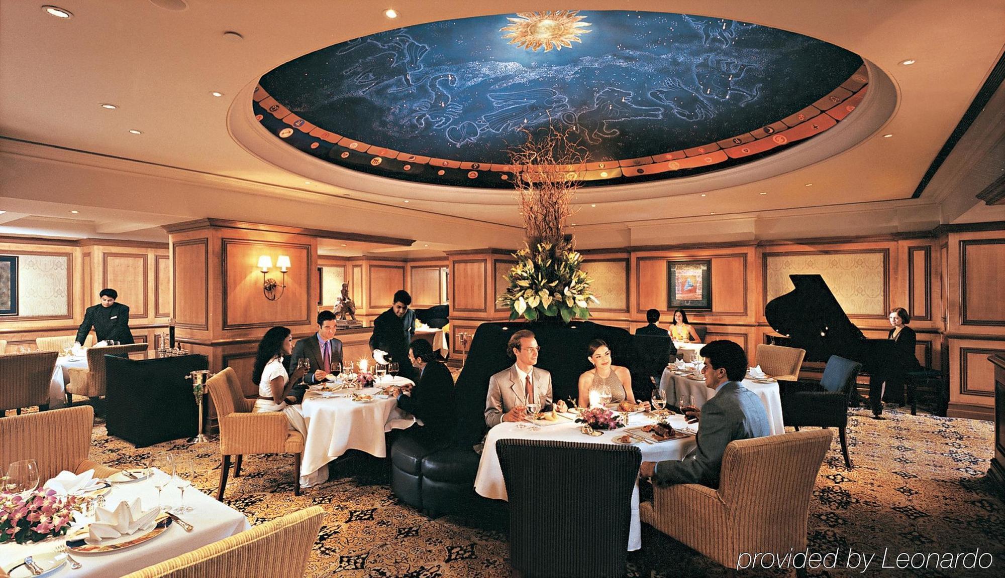 The Taj Mahal Tower, Mumbai Hotel Bagian luar foto The photo depicts an elegant dining room setting. The ceiling features a beautiful mural of the night sky, complete with stars and a shining sun. There are several tables set for dining, each with white tablecloths, flowers, and fine dining arrangeme